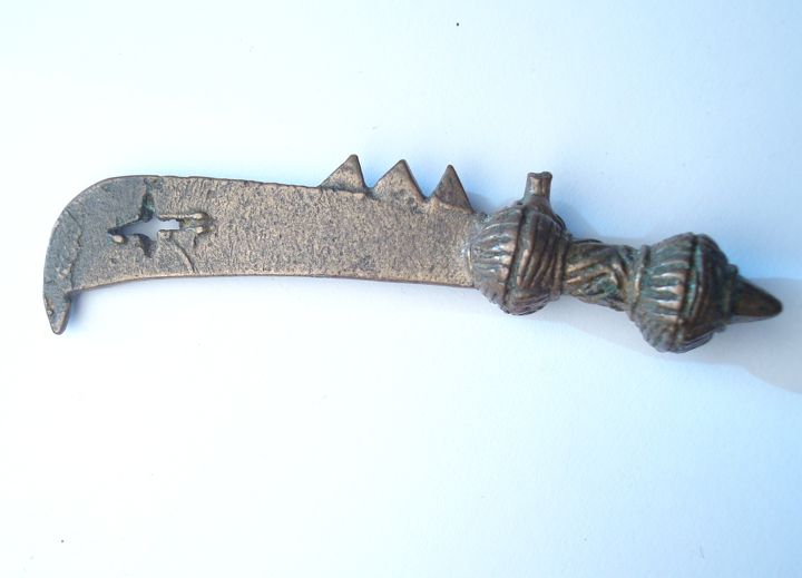 A bronze dagger with a curved blade and decorative grip, showcasing intricate designs and a pointed tip.